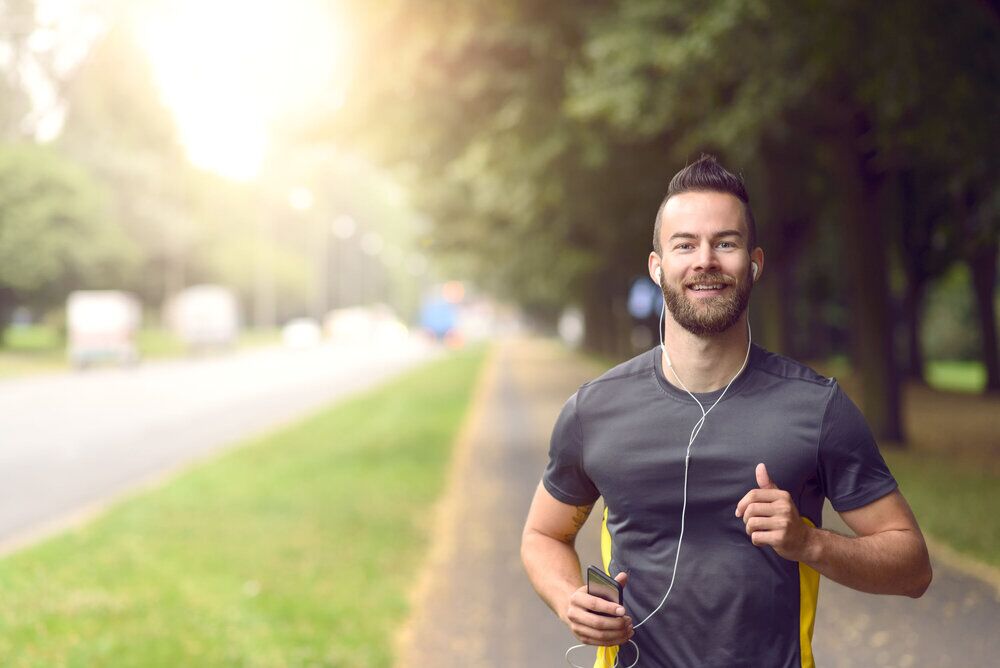 Man jogging along a sidewalk on a busy road